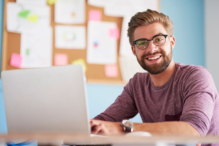 Χαρούμενος άνδρας δουλεύει με το laptop του στο managed WordPress hosting